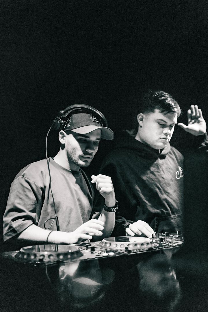 Black and white: the duo working the mixer side by side, one cueing on headphones.